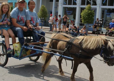 Three young ladies riding a pony carriage in the Apple Butter Festival in Spencer, IN.